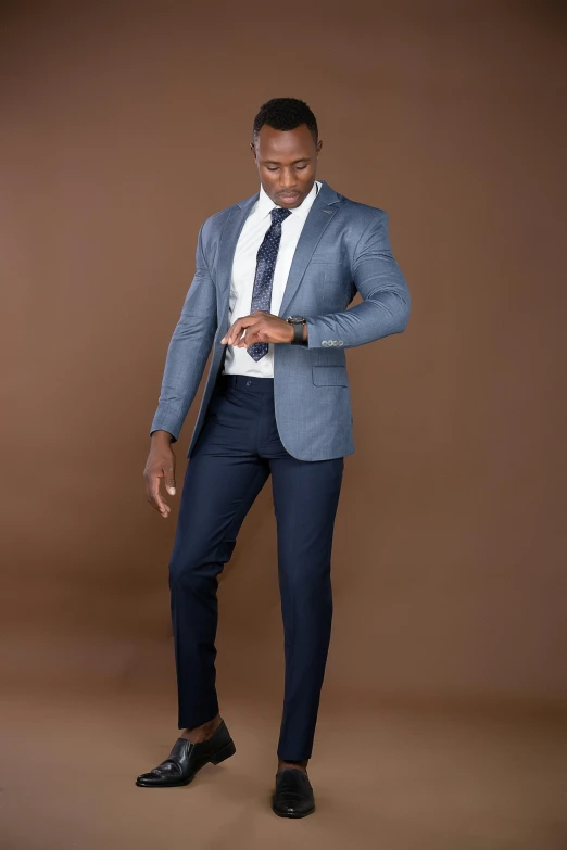 man in blue suit standing with brown background