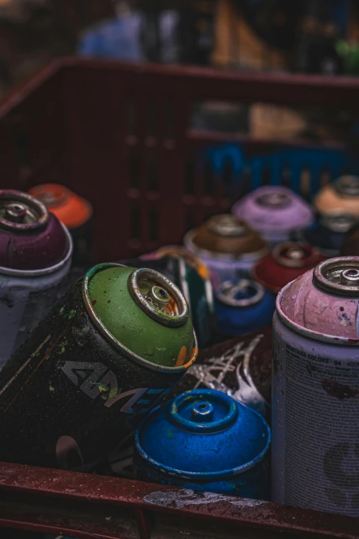 some cans with purple and blue paint sitting in a bin