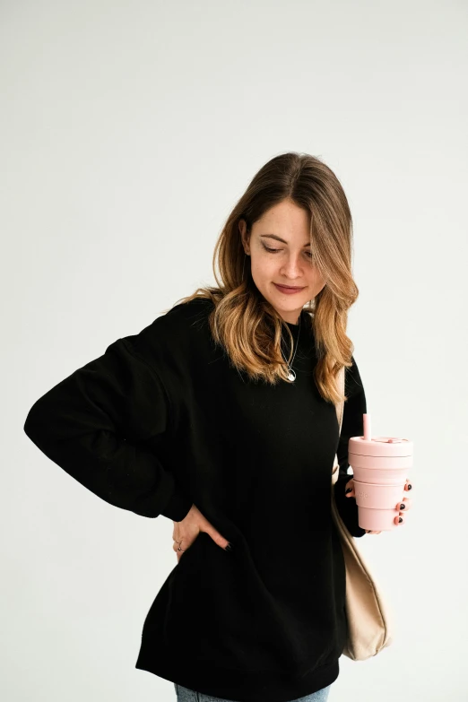 a woman standing next to a table holding a pink cup