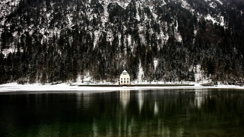 a building sitting on the side of a river next to a forest