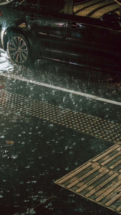 a black car sits on the street in the rain