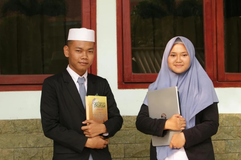 a man and a woman wearing muslim attire holding laptops