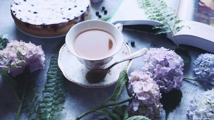 a cup with coffee sits on top of a saucer and flowers