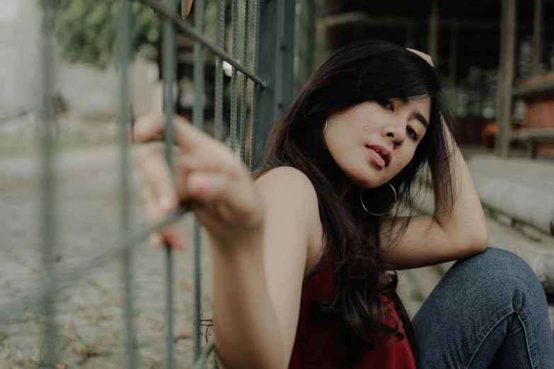 a young woman leaning against a fence posing for the camera