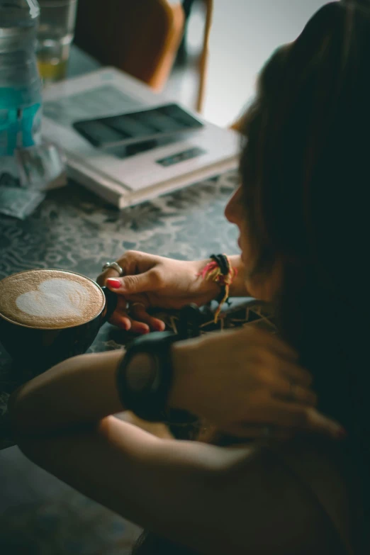 a woman sitting at a table with her hand on a coffee cup