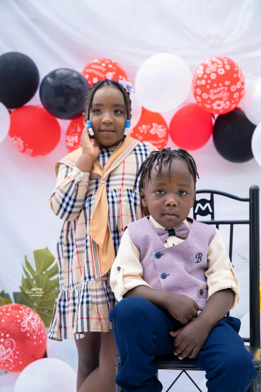 two young children sitting in front of balloons