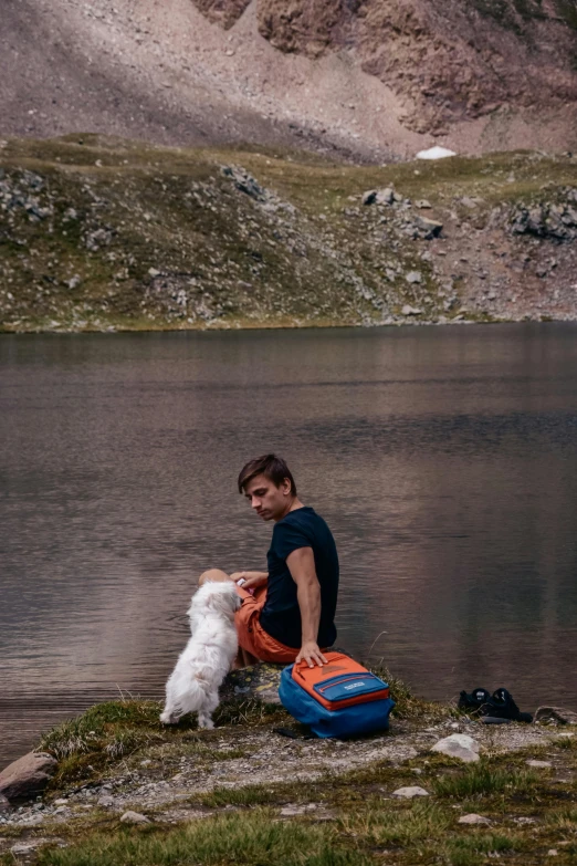 a person sitting on a rock with a dog