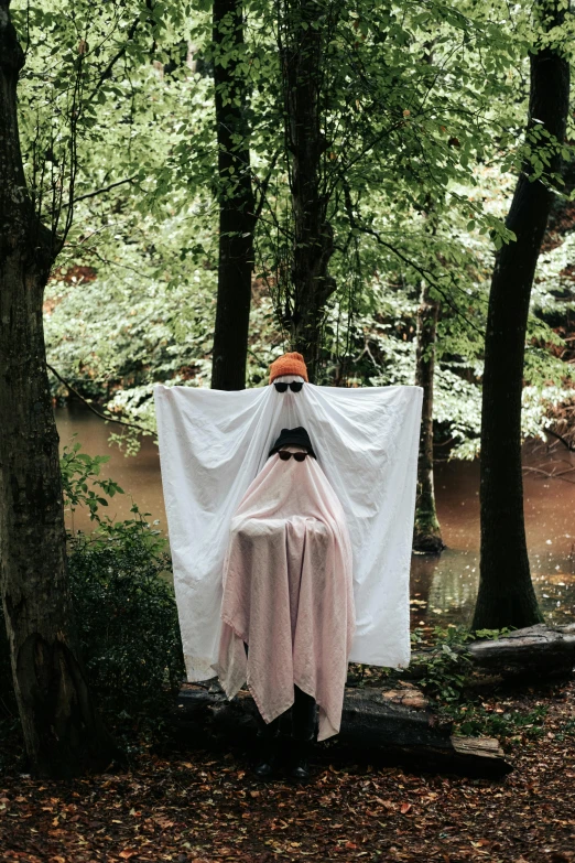 a creepy girl covered up with a white blanket and hanging her head