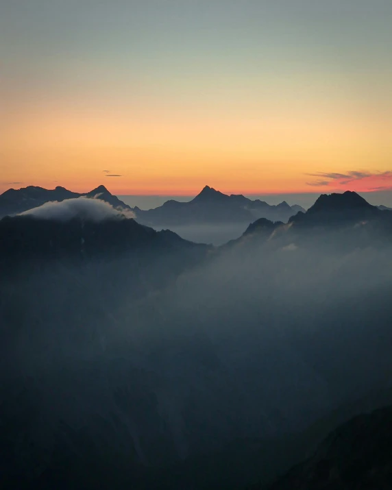 a sunset on a mountain top with mist and low lying clouds