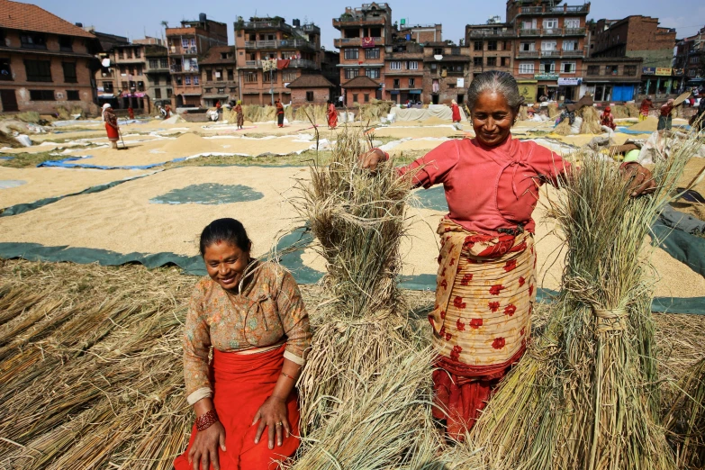 two women in bright red dress near hay stacks