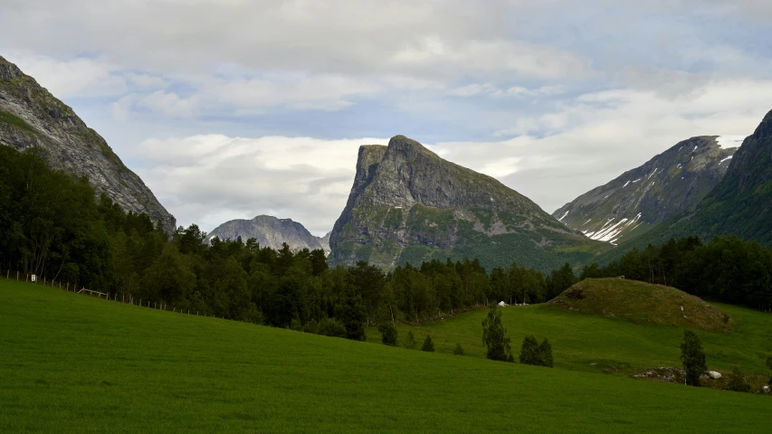 the mountains are very high and there is green grass on the ground