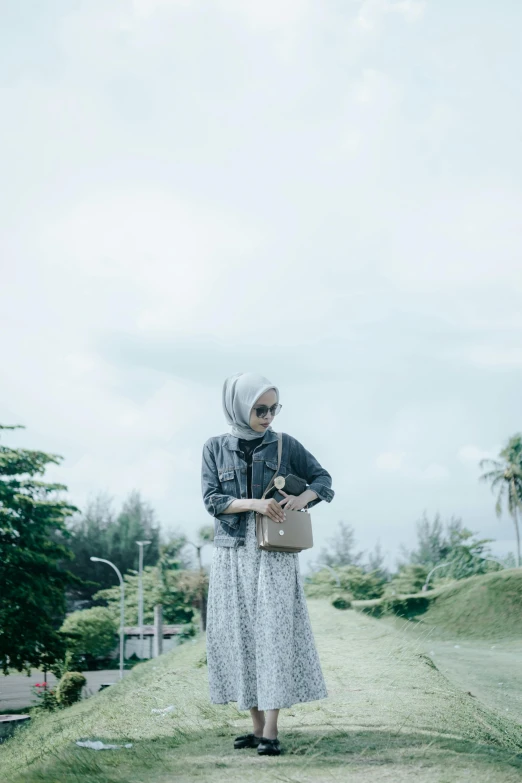 a woman in a gray dress standing on a hill