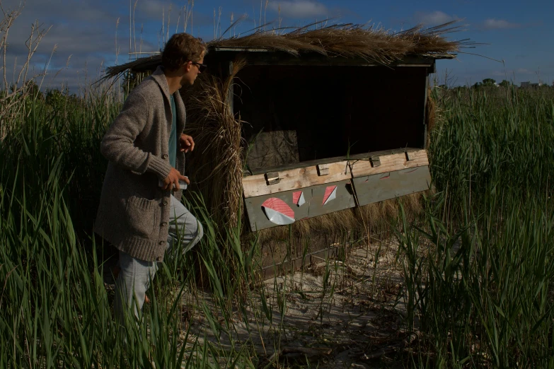 a person standing next to a shed in tall grass