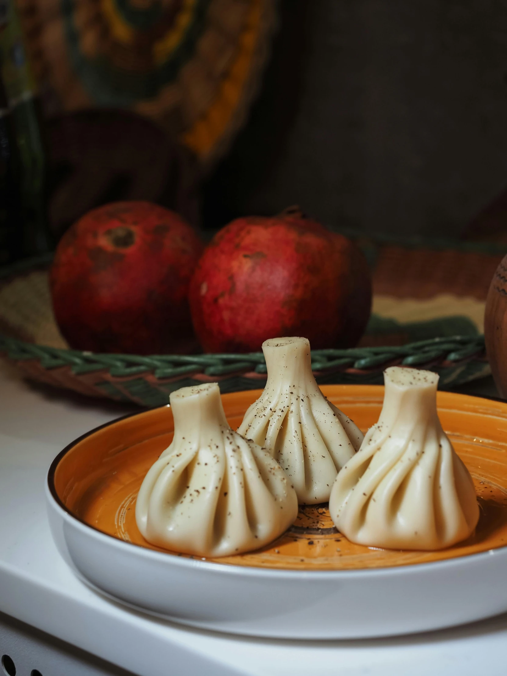 two asian dumplings on an orange plate in front of apples