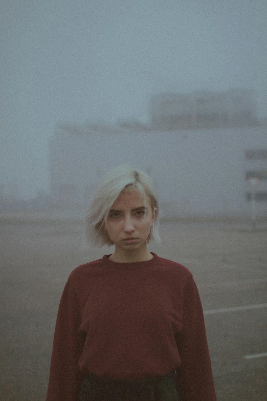 a woman with blonde hair stands in the fog