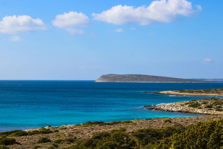 a view of an ocean with hills and blue water