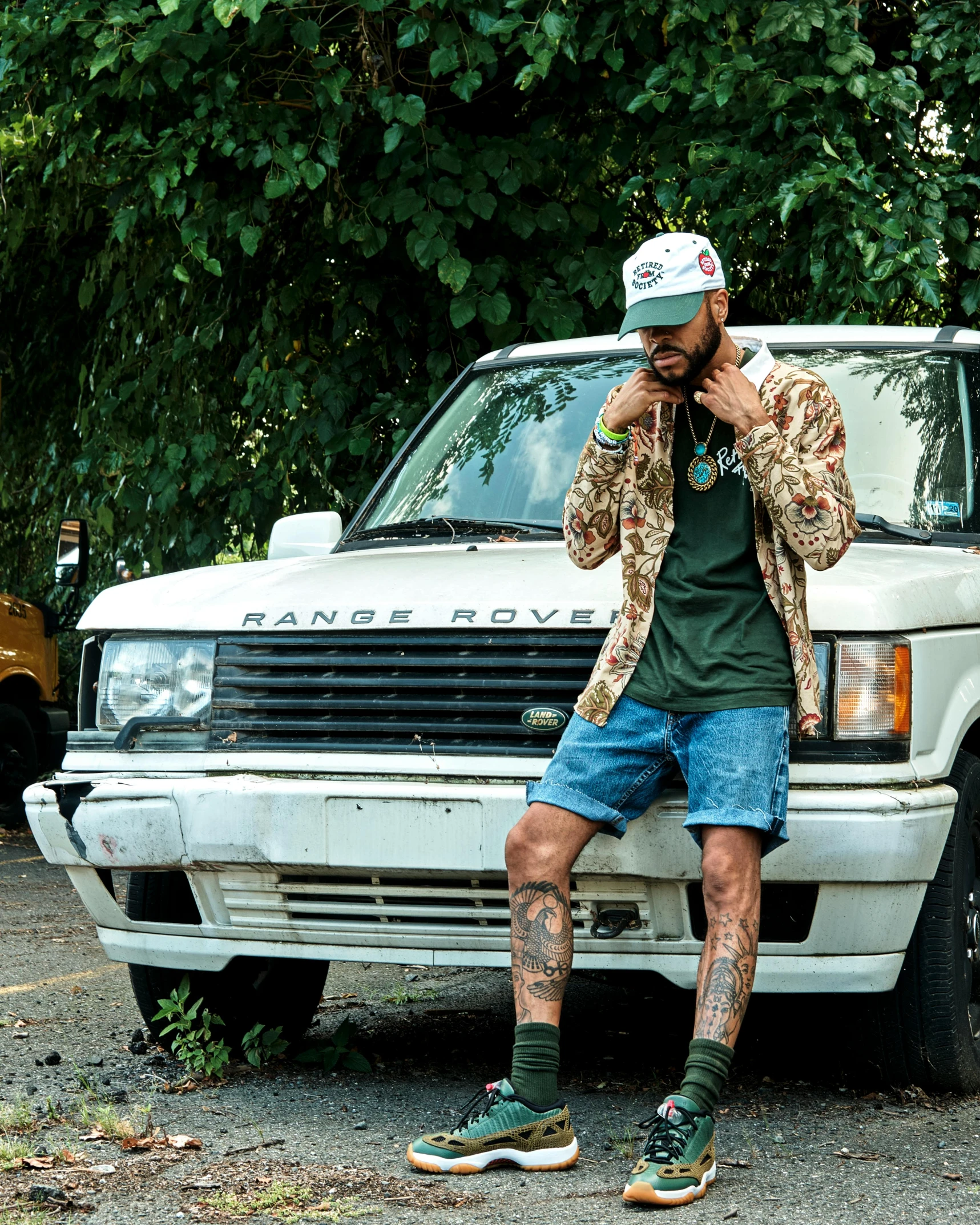 a man sitting on the hood of a car on his cell phone