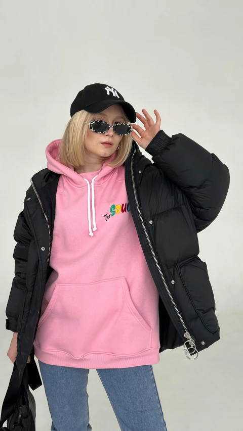 young woman posing in a black puffer jacket and matching pink shirt