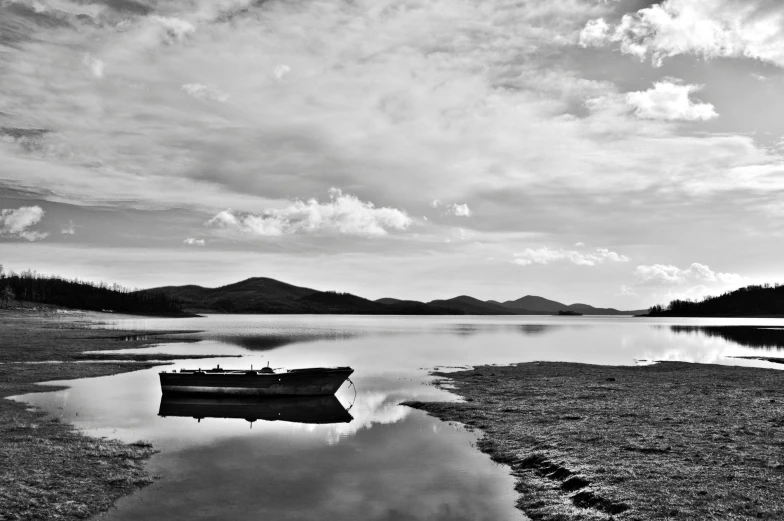 a small boat sits in the shallow water on a cloudy day