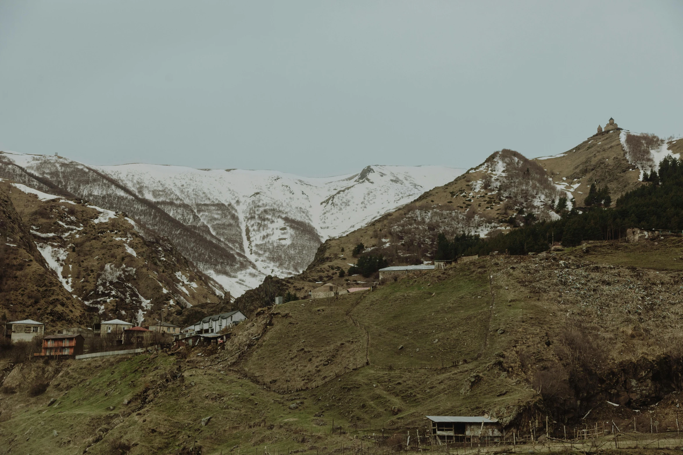 the mountains are covered in snow with houses on the top of them