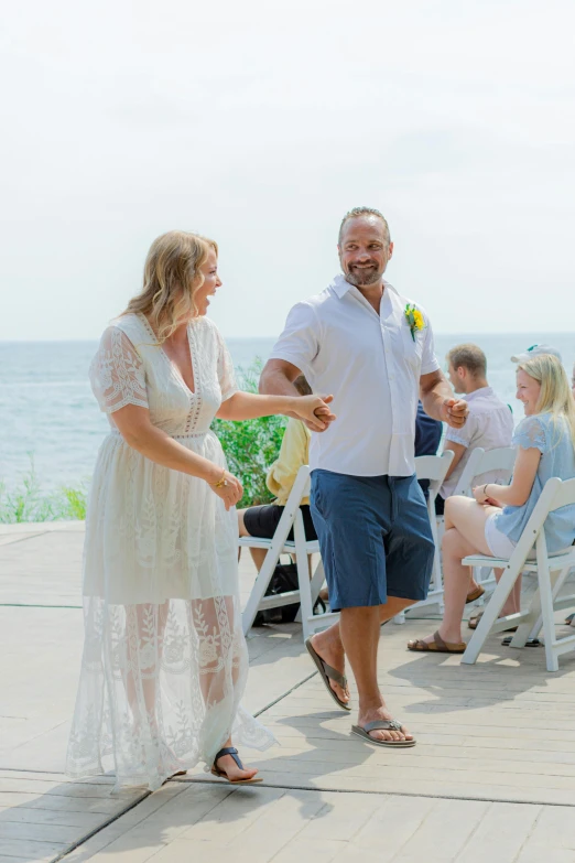 a man and woman holding hands while standing in front of an ocean