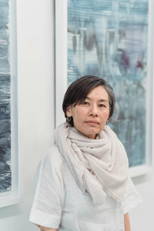 a woman with dark hair is standing next to two paintings