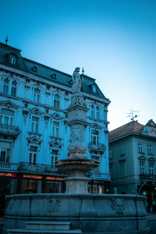 a fountain in front of a building at dusk