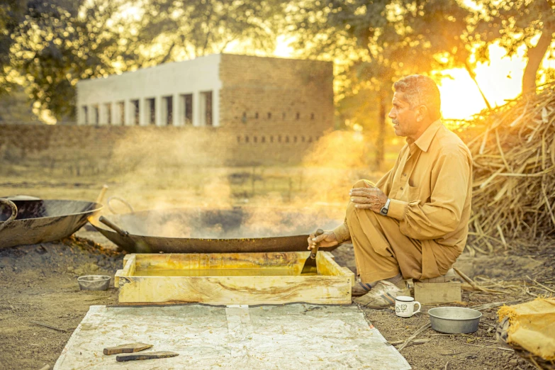 a man sitting in front of a stove holding a large knife