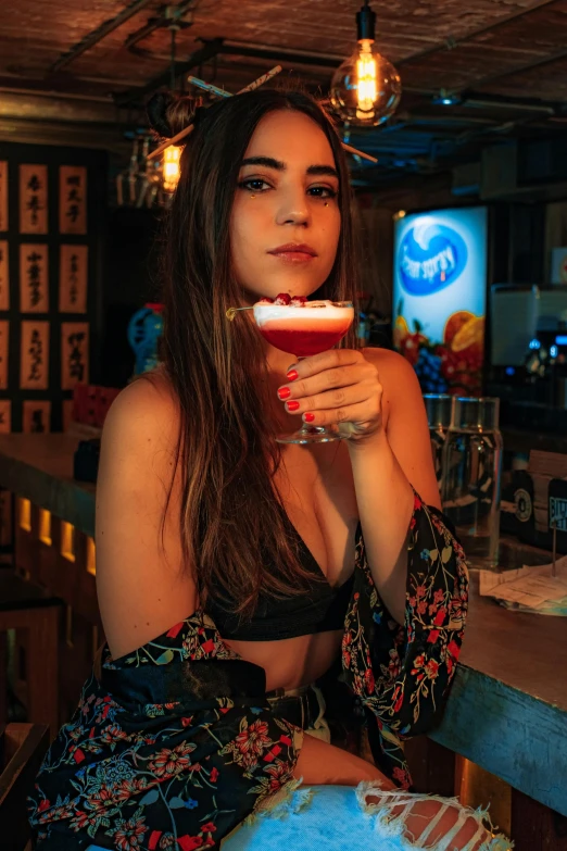 a woman posing in front of a glass filled with liquid