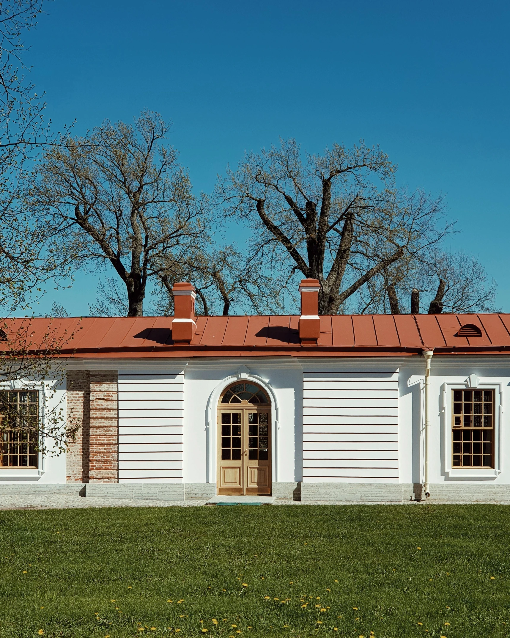 a white house with a red roof is next to some trees