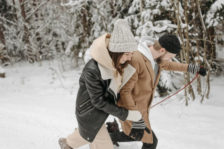 a woman in winter clothing holding the back of a snowboard while a man takes a po