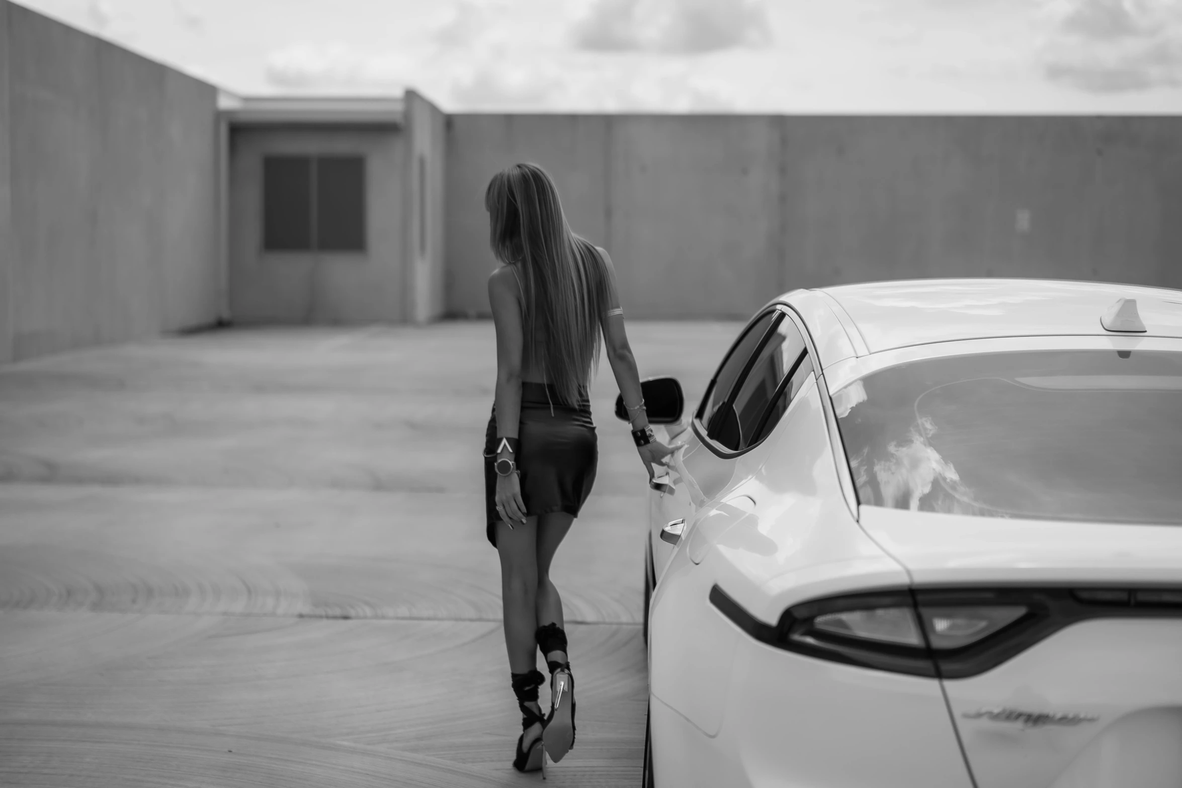 a girl in a short dress standing near a parked car