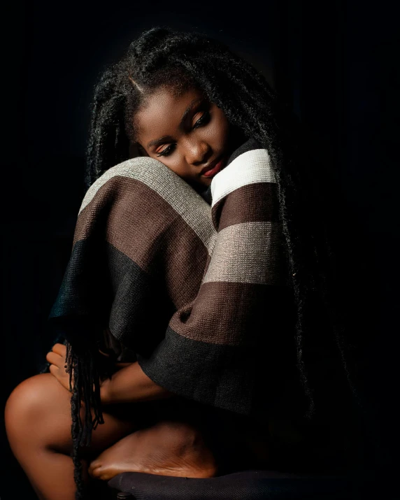 a girl sitting on a stool, wearing a striped shirt