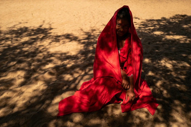 a woman with a red shawl sitting in the sun