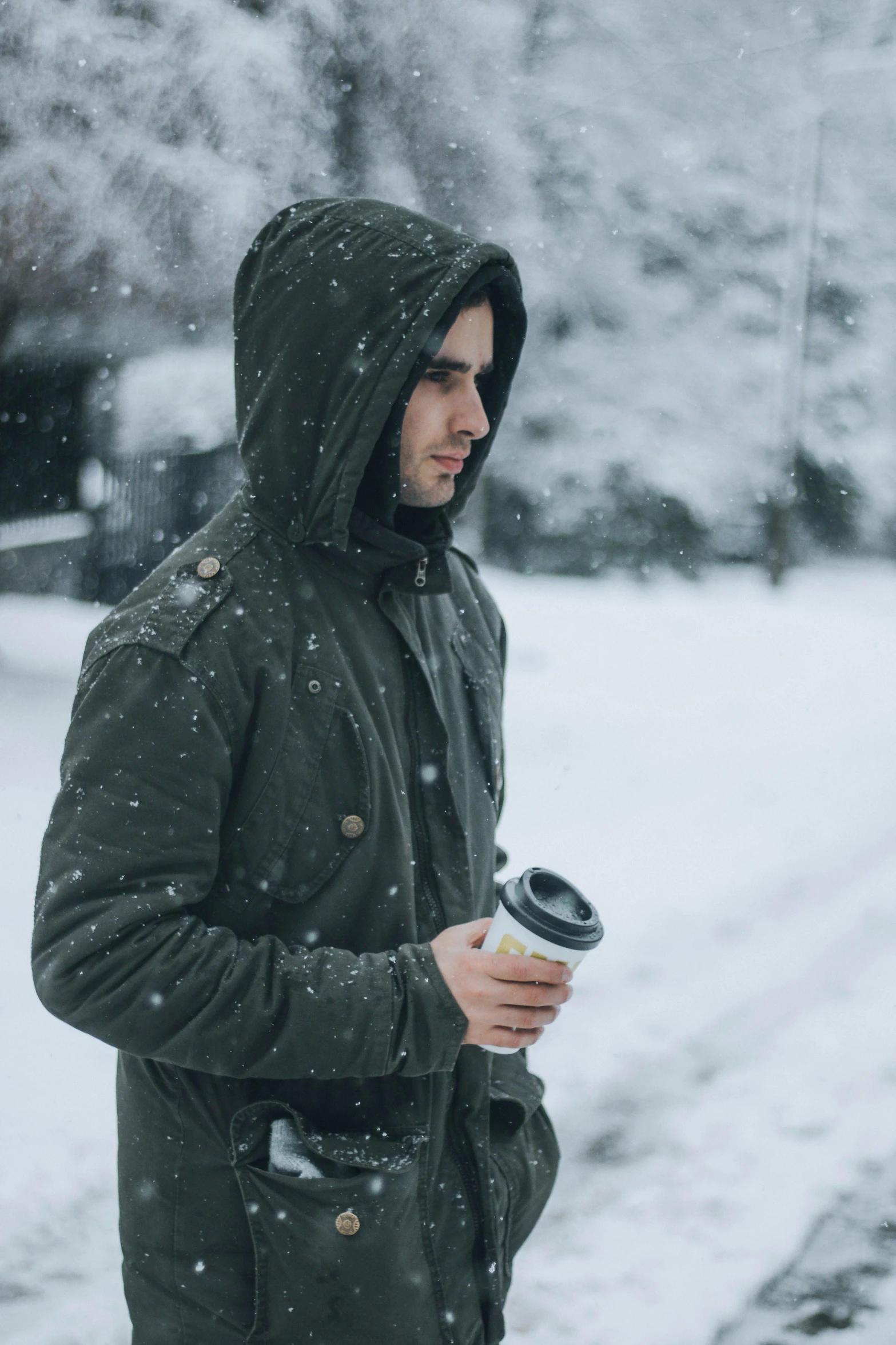 a young man walking in the snow with his drink