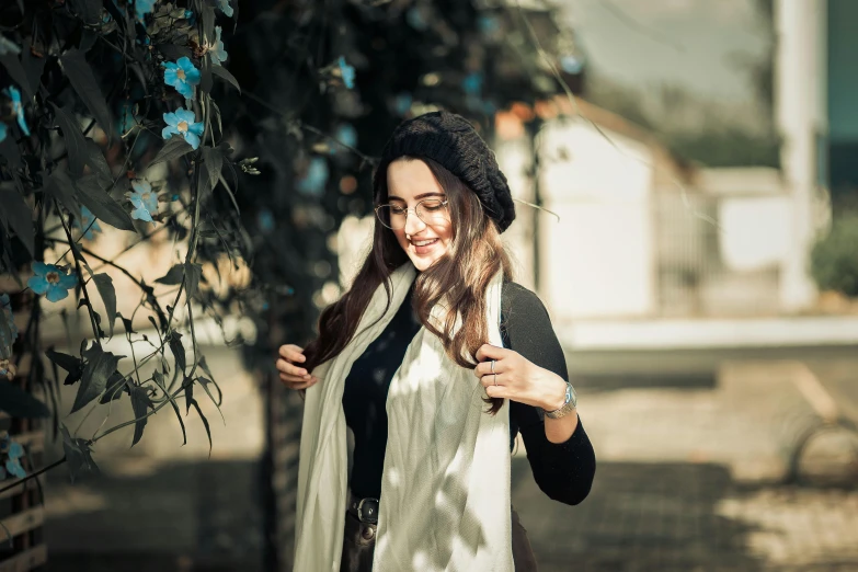 a beautiful woman in a black hat is standing outside