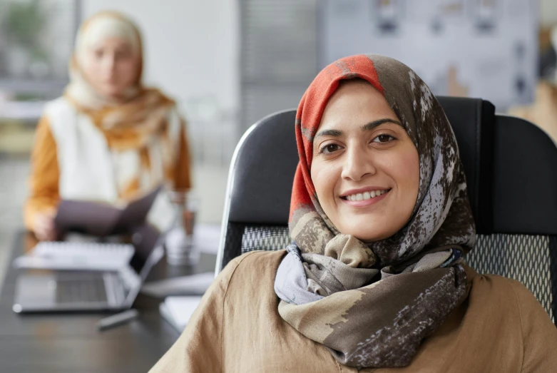 a woman with a scarf sits at a desk