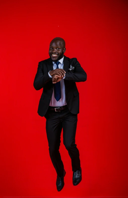 a man in a suit and tie standing in front of a red background