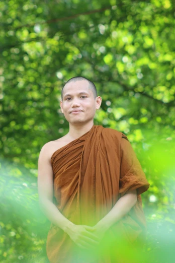 the young monk in the robe stands outside
