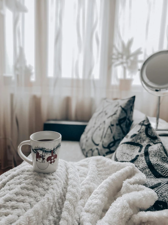 a cup sitting on top of a bed under a blanket