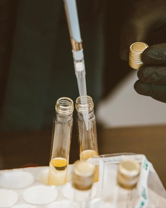 someone putting some pill in bottles next to gold rings