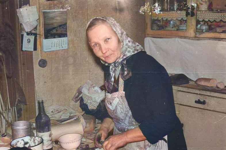 the old woman is wearing a long scarf near the counter