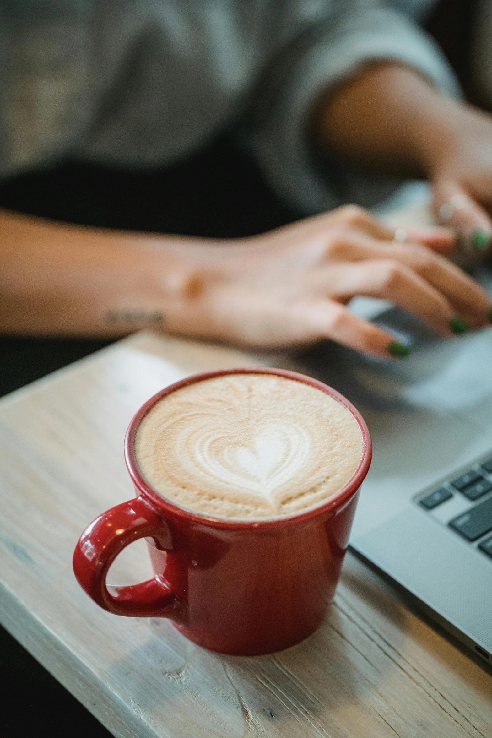 a cup of coffee sits on a table, with a laptop in front of it