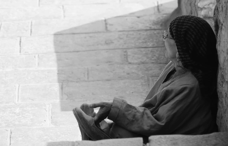 a person leaning against a wall in an alley