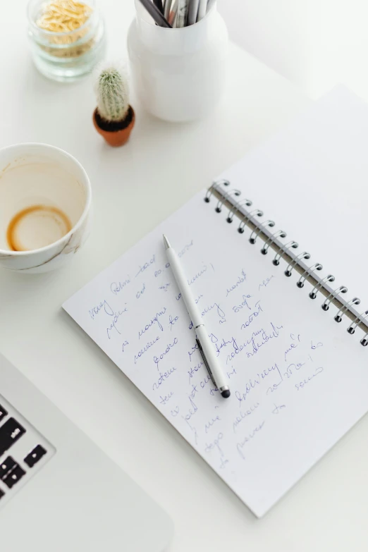 there is a notebook, pencil, paper and coffee on the desk