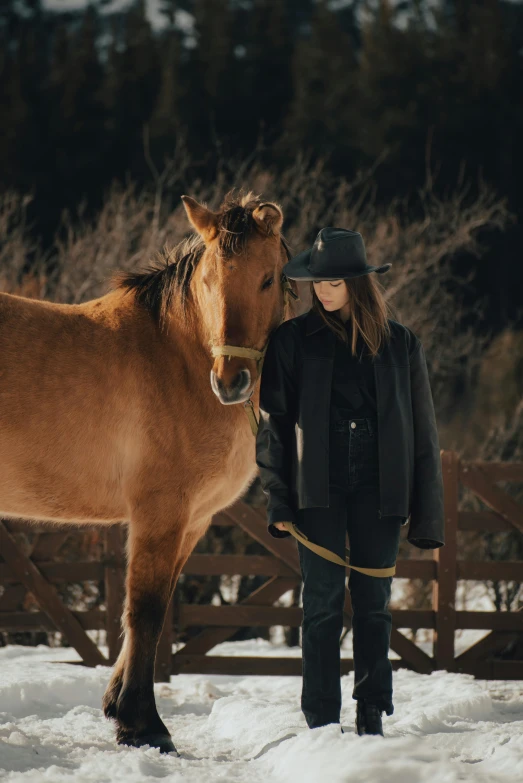 a young person wearing winter clothes is petting a large horse