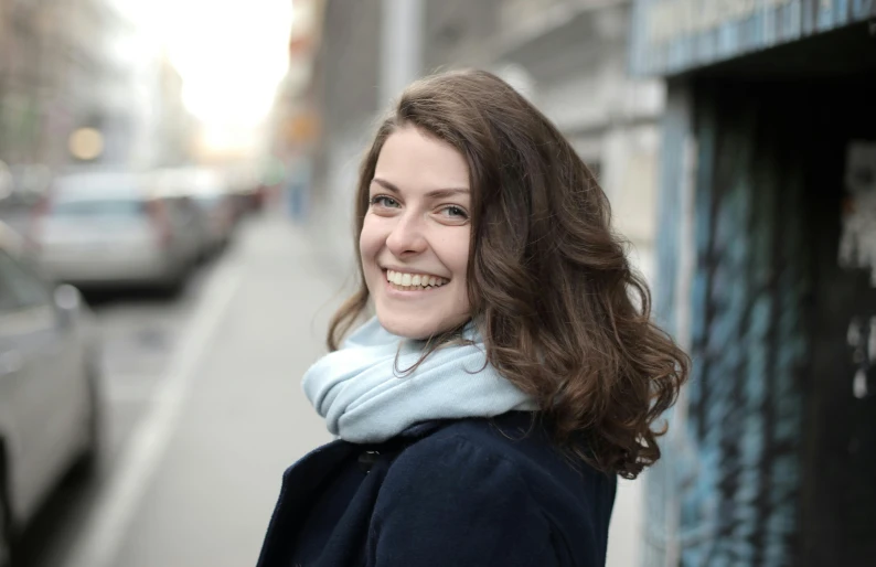 a woman standing next to a building wearing a blue coat