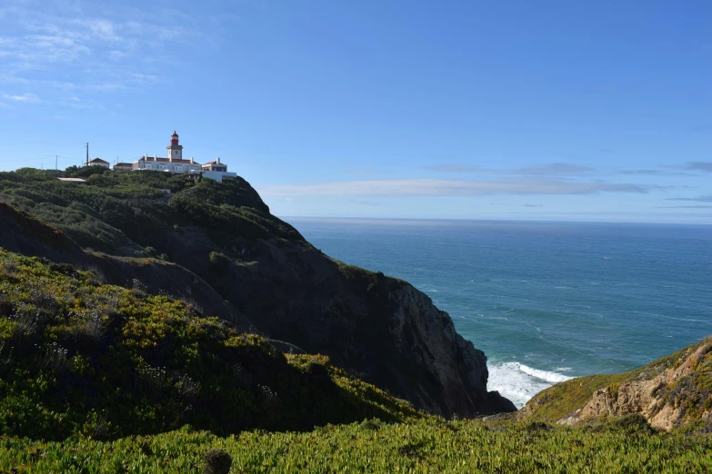 the lighthouse sits high on the rocky, green hill