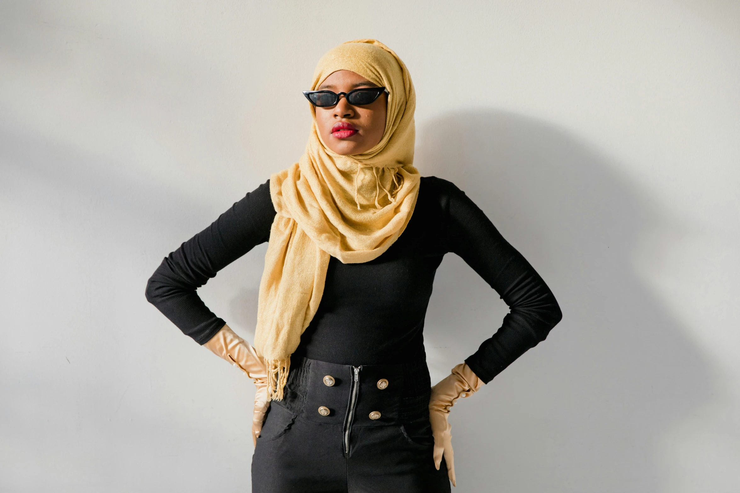 a woman in a black top and black jeans is wearing a scarf over her head