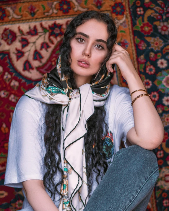 a woman wearing scarf and denim pants sitting down